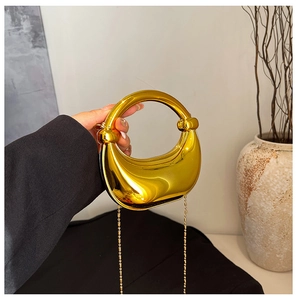 Detail einer glänzenden goldenen Halmondtasche mit Rundgriff und Metallkette