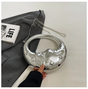 Detail of silver crescent moon clutch with metallic mirror finish and star embossing