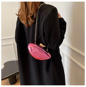 Detail of metallic pink lip-shaped bag with gold chain strap on black blazer jacket