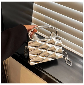 Detailed view of silver quilted metal hard shell clutch with lion head accents and chain