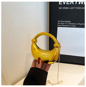 Nahaufnahme der glänzenden goldenen Mondsichel-Tasche mit Metall-Finish und Kette