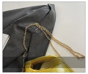 Detail of elegant gold chain shoulder strap on a grey blazer showing metallic texture
