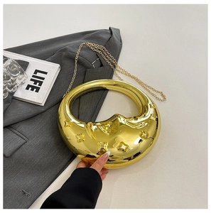 Macro detail of golden crescent clutch with embossed stars and metallic mirror finish