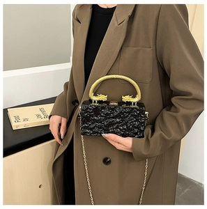 Detail of black textured evening bag featuring ornate gold dragon-shaped metal handles