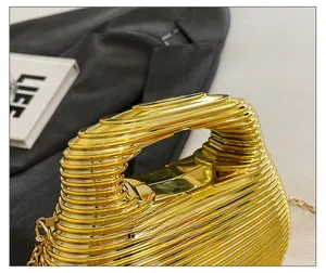 Macro detail of golden evening clutch with wavy texture and sleek integrated handle