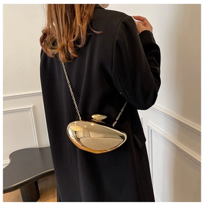 Detail of golden pebble-shaped evening clutch with glossy mirror finish and metal chain