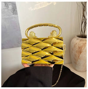 Detail of gold evening bag featuring lion head handles and diamond-cut texture finish