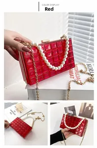 Détail du sac boîte en acrylique rouge avec anse perles et chaîne dorée