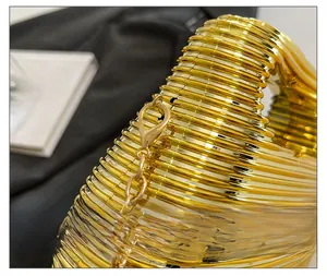 Macro detail of the golden textured metal surface and chain strap on this party bag