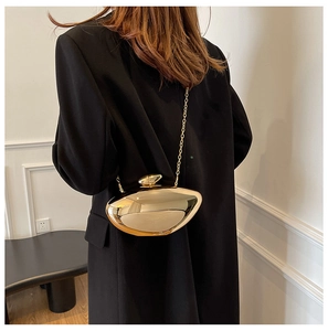Detail of irregular pebble-shaped gold metal clutch bag with mirrored finish and chain