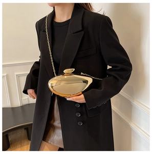 Close-up of gold asymmetrical clutch bag with fine chain and metallic mirror finish