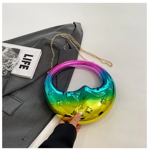 Detail of moon-shaped holographic handbag featuring star texture and gold chain strap