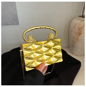 Detailed view of gold hard shell evening bag with 3D diamond pattern and lion head decor