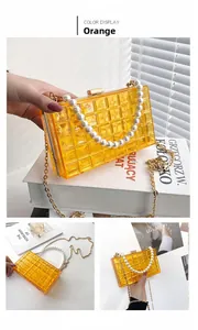 Détail du sac boîte orange en acrylique avec poignée en perles et chaîne dorée