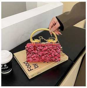 Detail of red textured acrylic clutch bag with gold dragon-shaped handle and metal chain