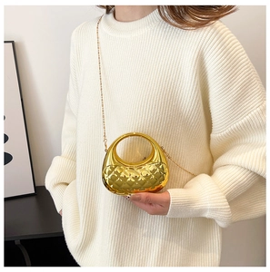 Detail einer metallisch goldenen Halbmond-Tasche mit Steppmuster und Metallkette