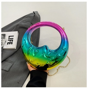 Detail of holographic moon shaped handbag with 3D face relief and gold chain strap