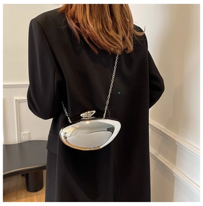 Detailed back view of a silver oval clutch bag with metal chain strap on a black blazer