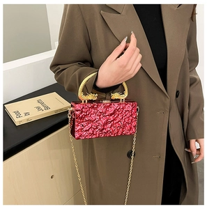 Macro view of red textured acrylic clutch featuring intricate golden dragon handle and chain