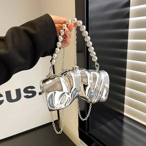 Unregelmäßige silberne Metallic-Clutch mit Perlengriff und Kettenriemen in der Hand