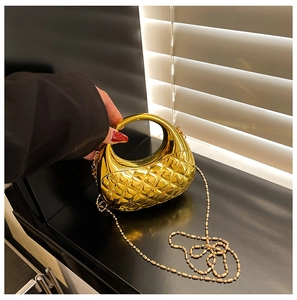 Detail der goldenen Metallic-Abendtasche mit Steppmuster und eleganter Perlenkette-Riemen