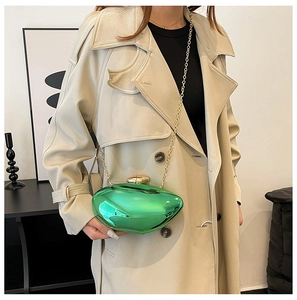 Macro detail of emerald green pebble-shaped acrylic clutch with gold chain strap