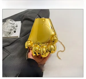 Détail d'un sac de soirée en forme de patte d'ours dorée avec finition miroir et chaîne