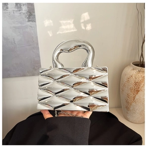 Macro shot of silver box bag with geometric rhombus pattern and curved metal handle
