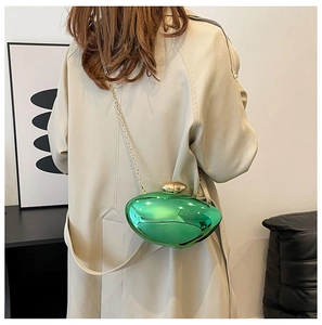 Detail of glossy emerald green hardshell clutch bag with elegant gold chain strap