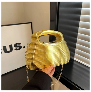 Detail of artistic wavy gold metallic evening bag with sleek geometric handle and chain