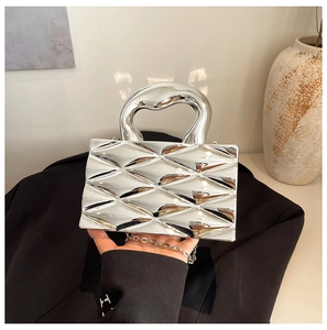 Close-up of a metallic silver box bag with 3D embossed texture and lava-style handle