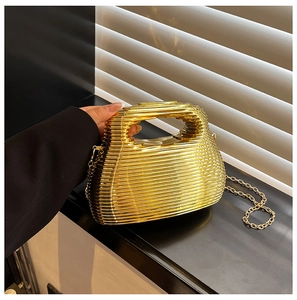Detail of a gold wave pattern clutch bag with metal handle and elegant chain strap
