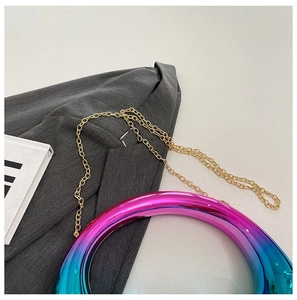 Top view of iridescent donut-shaped bag with gold chain strap on a grey suit jacket