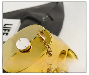 Détail de la pochette dorée miroir montrant le fermoir blanc et la bandoulière chaîne