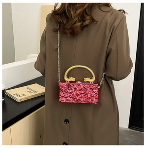 Red textured acrylic clutch bag with a gold dragon handle and delicate metal chain strap