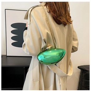 Detail view of green metallic hard-shell clutch bag with golden chain and egg-shaped clasp