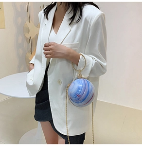 Detail of spherical marble handbag with blue and white planet pattern and gold ring handle
