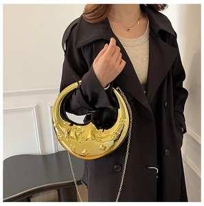 Detail of gold moon-shaped hard shell evening bag with star embossing and chain strap