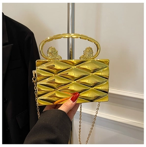 Detail of gold metal box bag featuring quilted texture and lion head handle attachments