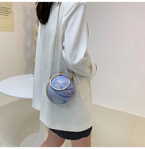 Detail of spherical marble texture handbag with gold metal handle and chain strap