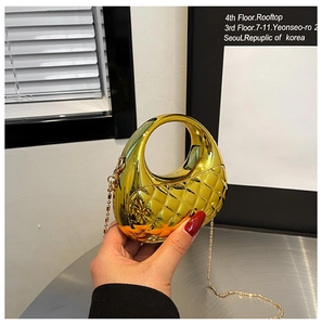 Detail der goldglänzenden gesteppten Mondsichel-Handtasche mit eleganter Metall-Kugelkette