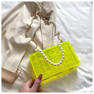 Détail du sac boîte en acrylique jaune fluo avec texture matelassée et perles