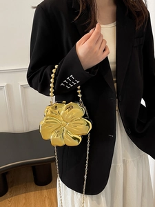 Detail of golden flower box bag with metallic plating and beaded handle on a model