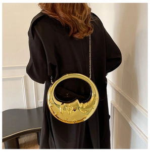 Close-up of golden crescent moon evening bag with star texture on a black coat