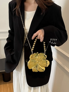 Detail of a golden flower-shaped purse with metallic finish and bead handle