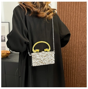 Detail of silver textured acrylic evening bag with ornate golden dragon handles