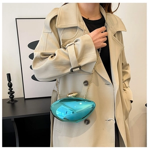 Detail of the turquoise shell evening bag with gold chain strap on a model shoulder