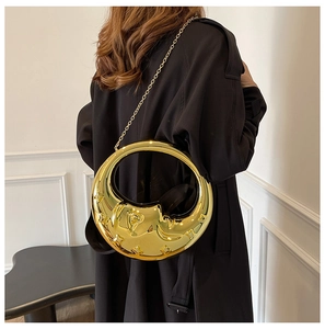 Detailed relief of moon face and stars on a shiny gold metallic crescent bag with chain