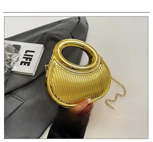 Close-up of golden metallic pleated handbag with round handle and chain strap details