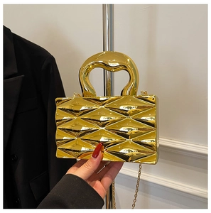 Detail of luxury gold metallic clutch with textured diamond pattern and thick handle